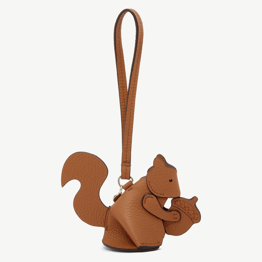 Tan squirrel leather bag charm holding an acorn with long wrist strap.